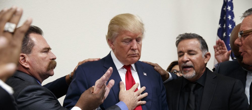 Donald Trump hat die Augen geschlossen und betet.