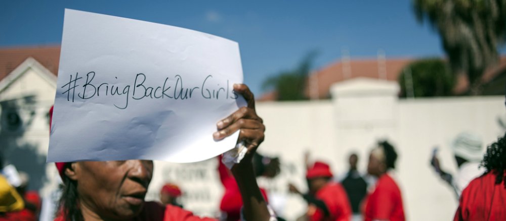 Ein Frau hält in Nigeria ein Protesschild mit der Aufschrift "Bring back our Girls" in die Luft.