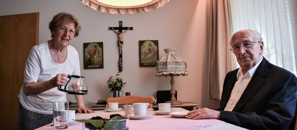 Haushälterin Annemarie Zill und Priester Max Knorr sitzen am Esstisch beim Kaffee