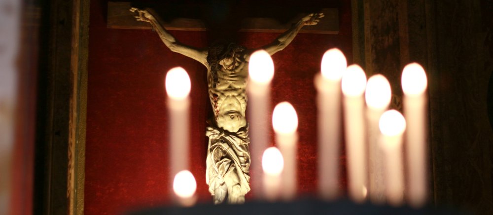 Sacrificial lights stand in front of a crucifix in the Jesuit church Il Gesu in Rome.