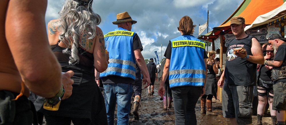 Zwei Festivalseelsorger gehen durch den Schlamm auf dem Gelände beim Wacken Open Air Festival