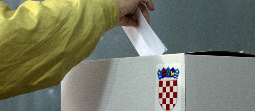 Ein Kroate wirft seinen Stimmzettel in die mit dem kroatischen Wappen geschmückte Wahlurne.