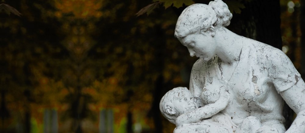 Skulptur einer jungen Frau mit Kind in einem Park.