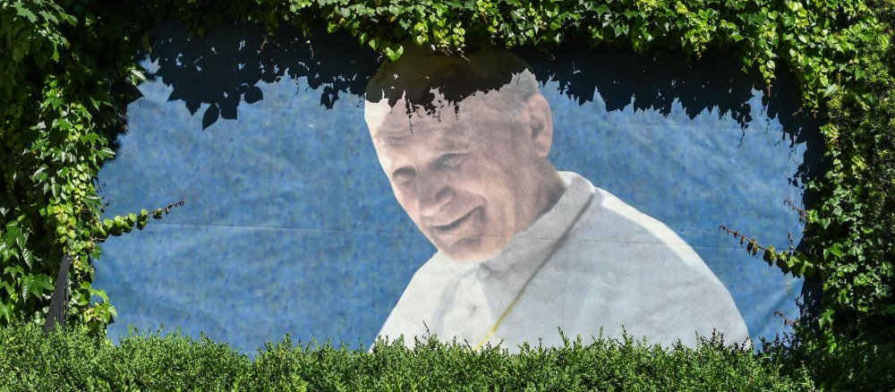 Ein Porträt von Papst Johannes Paul II., von Efeu umrankt.