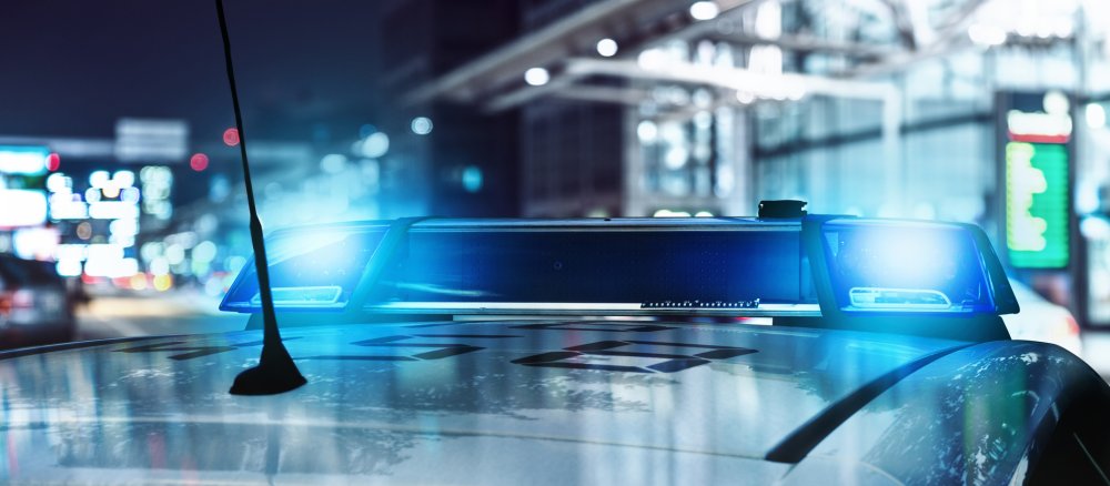 A police car is parked in a town with its blue lights switched on.