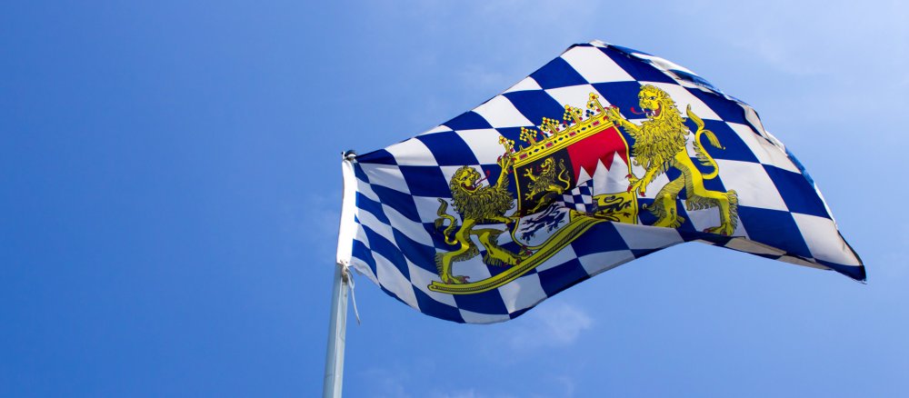 Die Flagge mit Wappen des Freistaats Bayern weht im Wind.