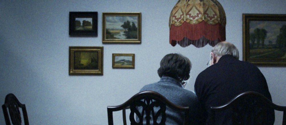 Rückansicht eines eng aneinandersitzenden Paares am Eßtisch im Wohnzimmer.