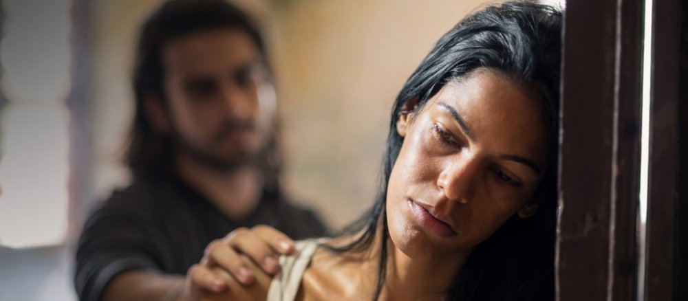 Ein Mann versucht eine Frau zu trösten und hat eine Hand auf ihre Schulter gelegt.