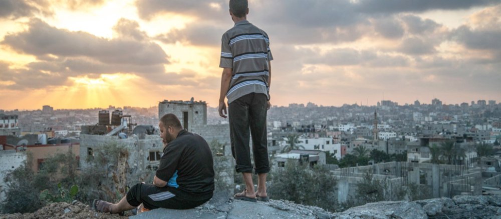 Zwei Männer blicken auf die zerstörte Stadt Gaza.