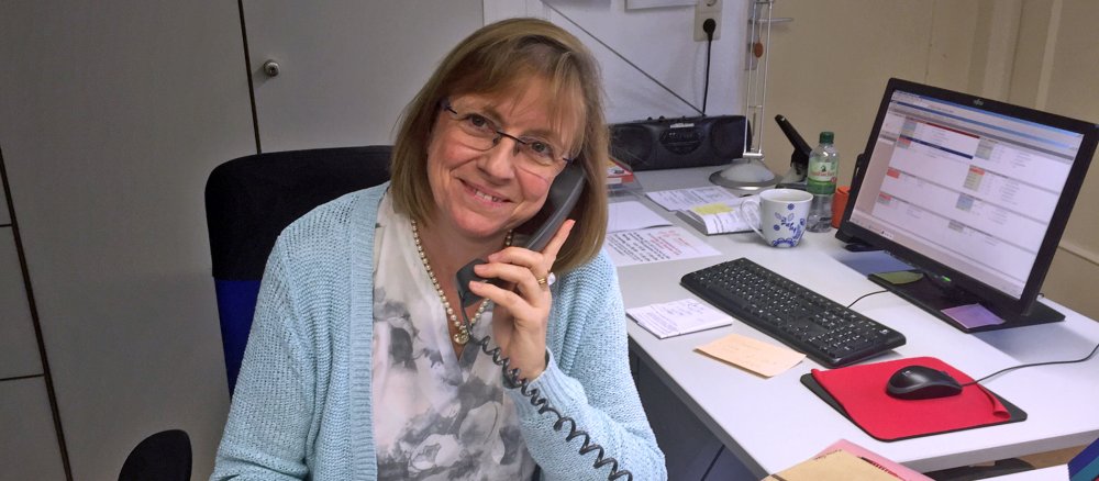 Die Pfarrsekretärin Martina Göbel telefoniert und lächelt.