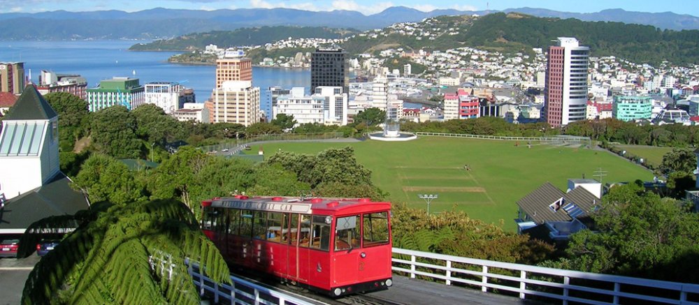 Blick auf die neuseeländische Hauptstadt Wellington. Im Vordergrund führt eine Straßenbahn