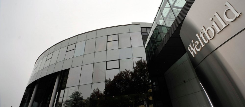 Ein rundes Glashaus vor einem wolkenverhangenen Himmel. Am rechten Bildrand ist das Firmenlogo mit der Aufschrift "Weltbild".
