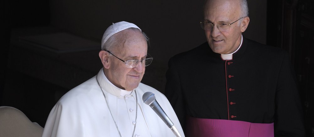 Alfred Xuereb stands to the right of Pope Francis, who places a sheet of paper on a lectern.
