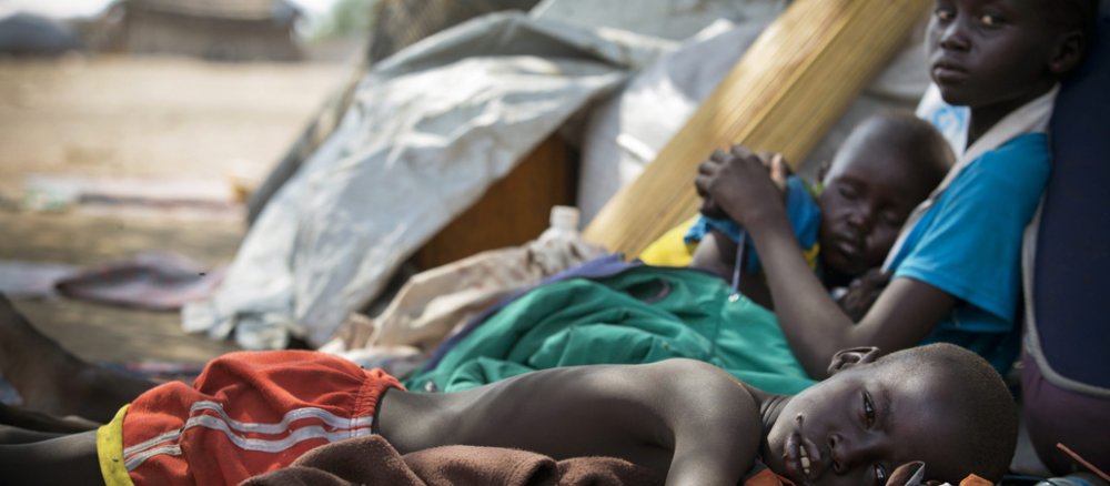 Kinder liegen vor einem Zelt in einem Flüchtlingscamp.