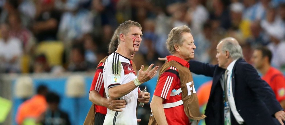 Bastian Schweinsteiger wird blutend vom Platz begleitet
