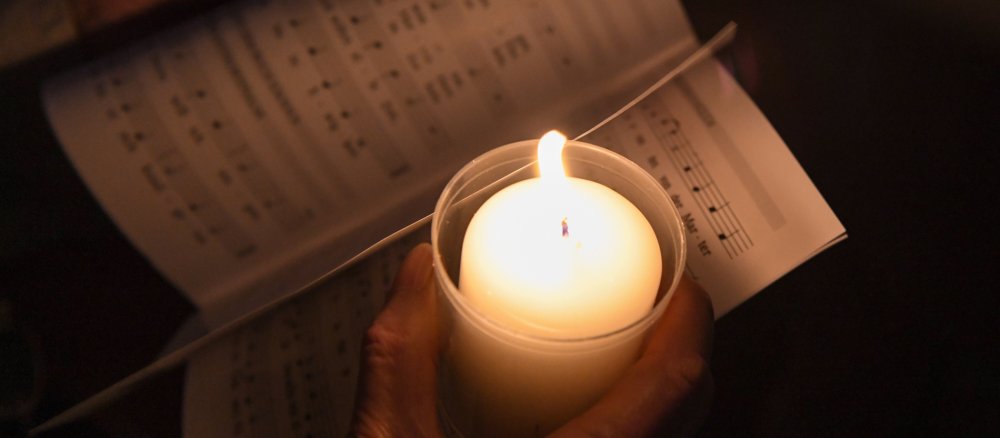 Eine Kerze beleuchtet die Seiten eines Gebetbuchs