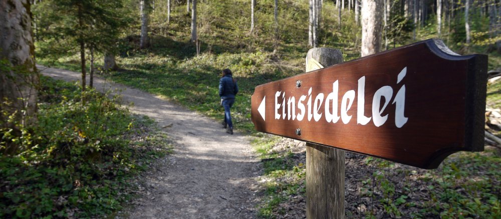 Ein Schild mit "Einsiedelei" steht in einem Wald