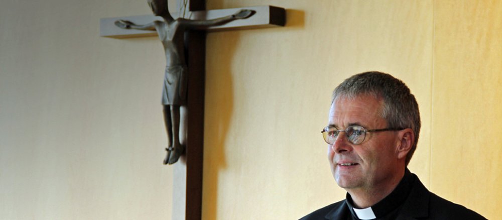 Wolfgang Rösch vor einem Kreuz in der Aula des Priesterseminars.