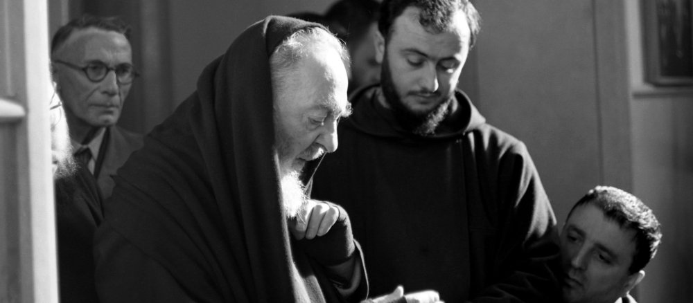 Padre Pio in habit with a confrere and faithful