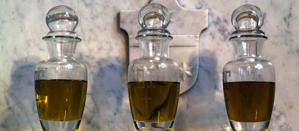 Drei mit heiligem Öl gefüllte Glas-Flacons stehen vor einer Marmorplatte: Das Katechumenenöl, das Krankenöl und das Chrisam.