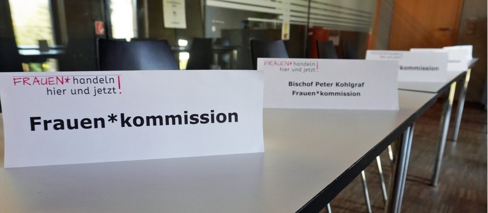 Schilder mit der Aufschrift "Frauen*kommission" stehen auf einem Tisch