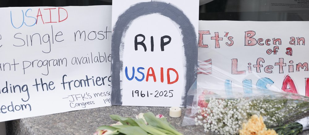 Plakate und Blumen mit der Aufschrift RIP USAID