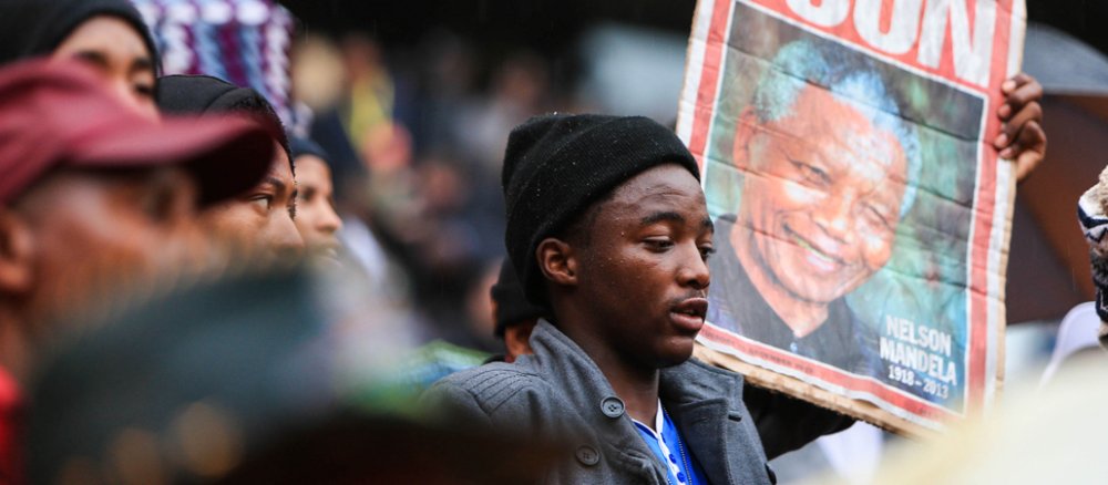 Ein Mann hält bei der Trauerfeier für Nelson Mandela ein Plakat mit dem Bild des Verstorbenen hoch.