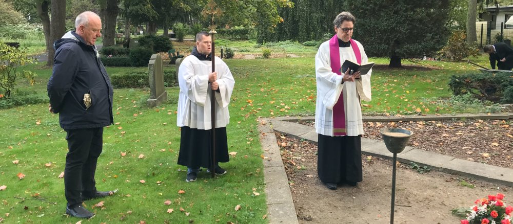 Drei Männer stehen auf einem Friedhof in Berlin