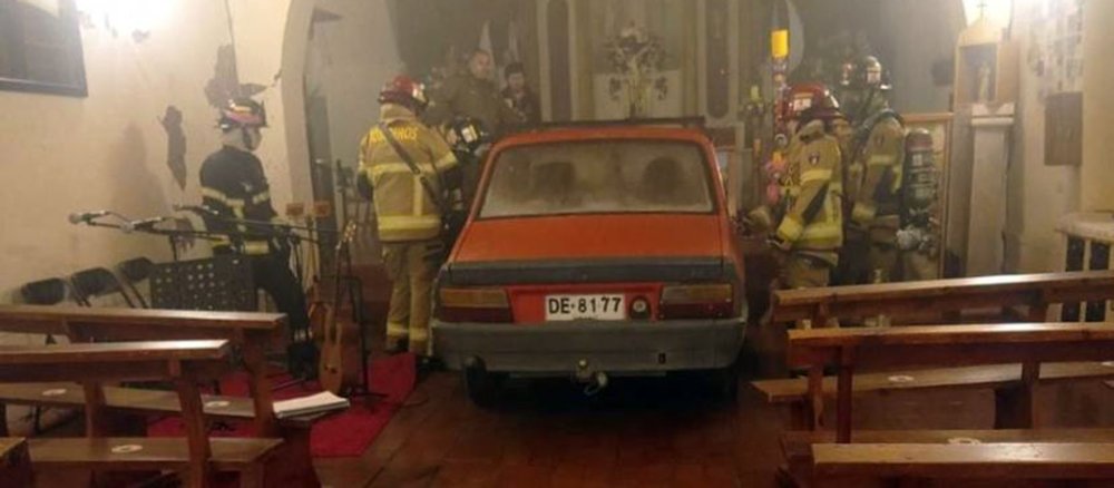 Ein Auto steht vor dem Altar der Pfarrkirche Nuestra Señora de la Merced in Zúñiga, Feuerwehrleute begutachten den Schaden