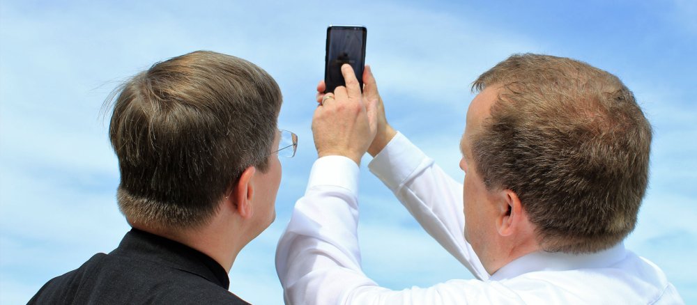 Pastoralreferent Martin Wichmann zeigt Erzbischof Stephan Burger die App zur Landesgartenschau.