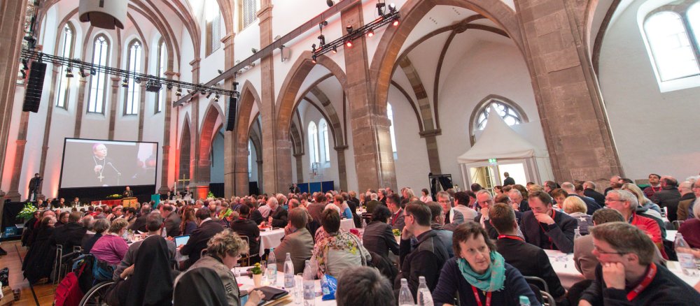 Menschen sind zu einer Tagung in einer Kirche versammelt.