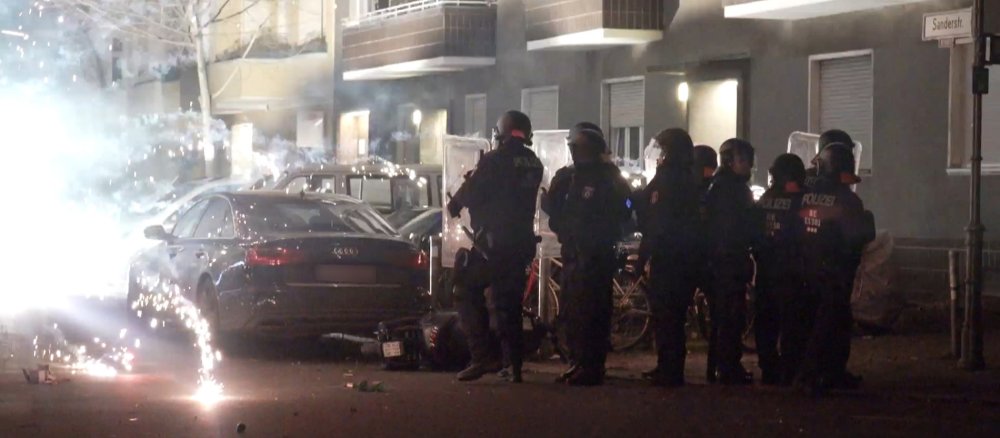Polizisten stehen hinter explodierendem Feuerwerk.