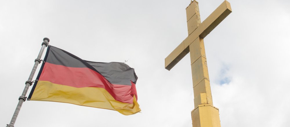 Eine Deutschland-Flagge und ein vergoldetes Turmkreu