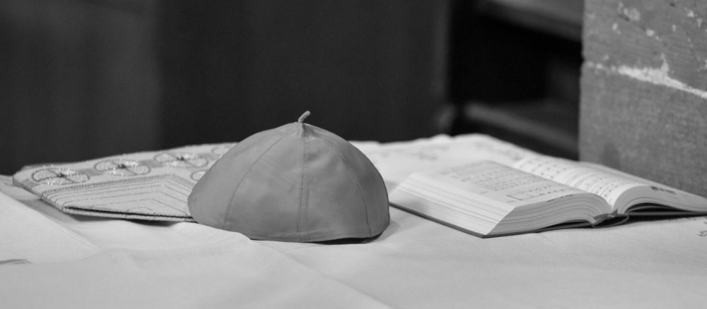 Ein Pileolus und eine Mitra liegen auf einem Altar