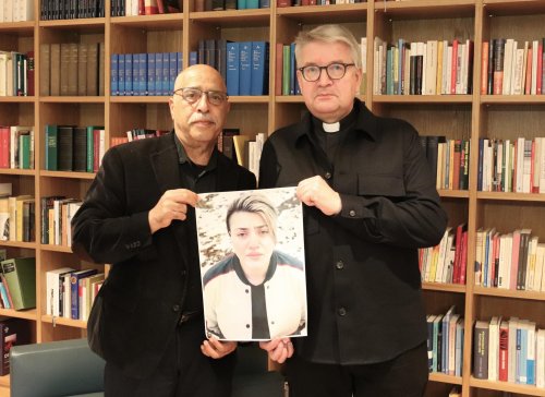 Behrouz Asadi (l) und Bischof Peter Kohlgraf halten ein Bild von Mahboubeh Shabani.