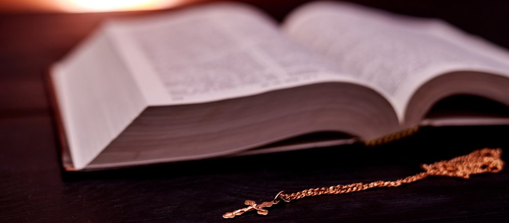 A cross necklace in front of an open Bible
