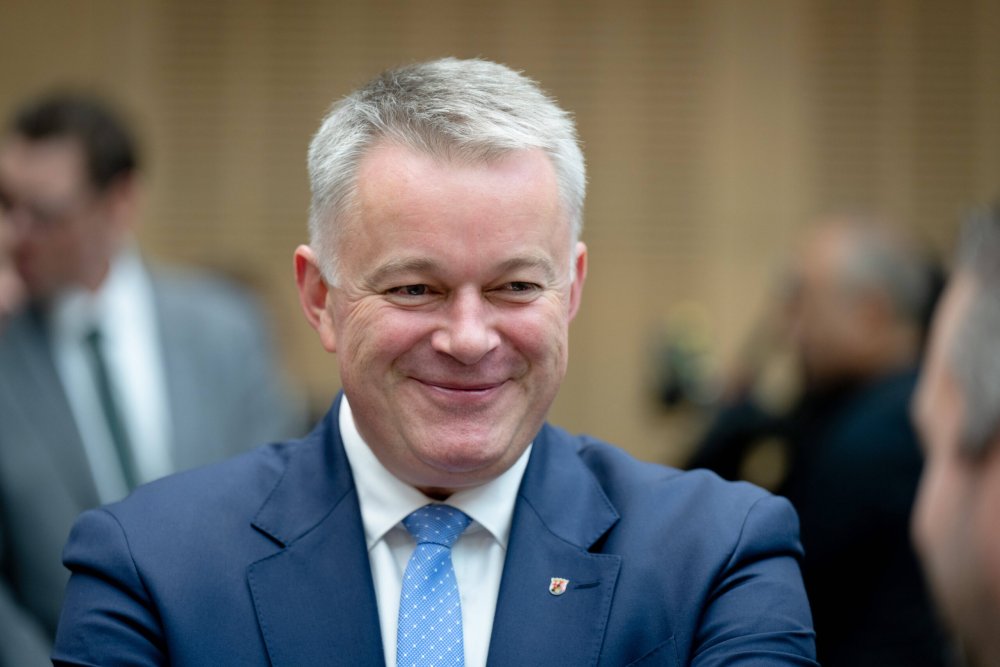 Ministerpräsident Gordon Schnieder lächelt im Gespräch einen Gesprächspartner an