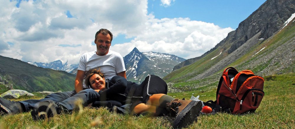 Ein Paar ruht sich im Gebirge auf einer Wiese aus.