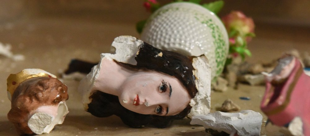 Eine zerbrochene Heiligenfigur liegt auf dem Boden