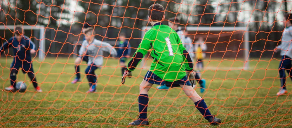 Ein Junge steht beim Fußballspielen im Tor.