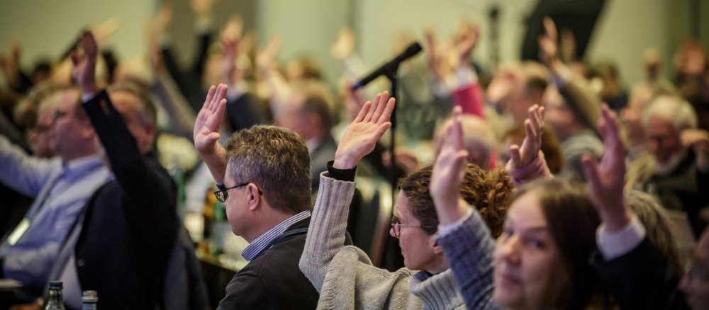 Members raise their hands during a vote