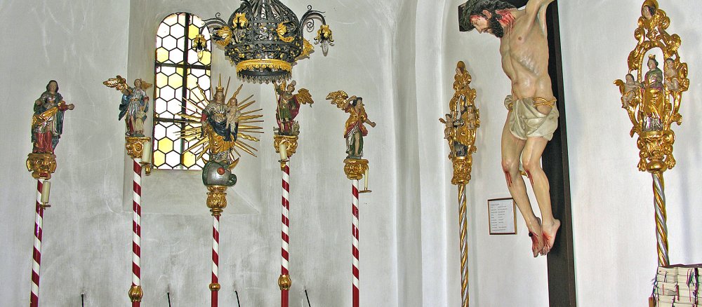 verschiedene Stäbe mit Heiligenfiguren und ein Kreuz