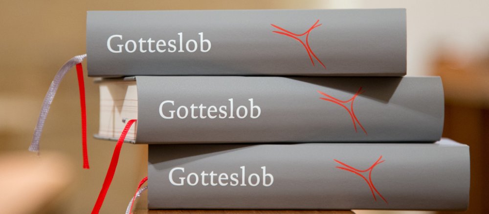 Drei neue Gotteslöber liegen übereinander gestapelt auf der Kirchenbank.