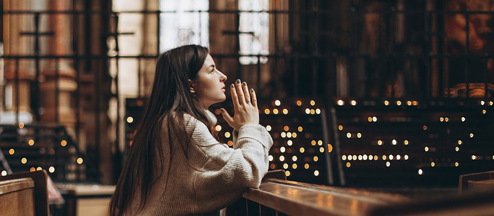 Eine junge Frau betet in einer Kirche.