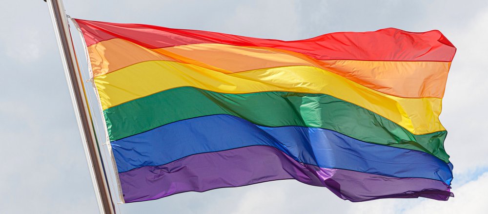 Eine Regenbogenfahne weht im Wind.