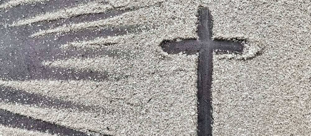 Ein Kreuz ist in Asche gemalt
