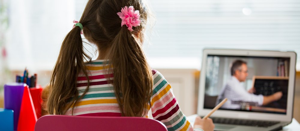 Ein Mädchen sitzt vor einem Laptop und verfolgt den Online-Unterricht.
