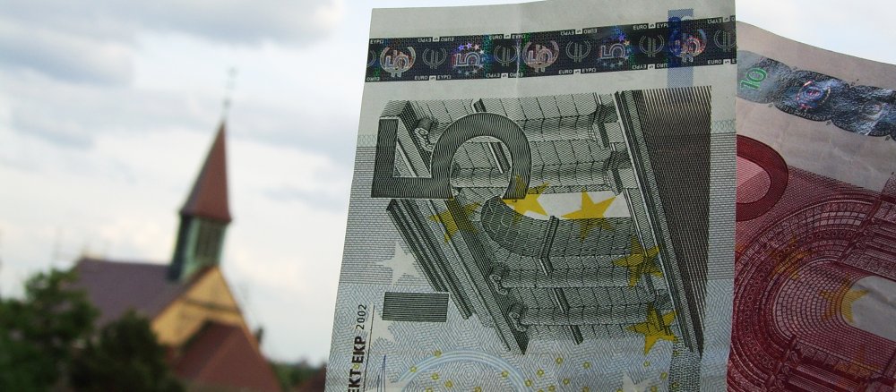 Geldscheine vor einem Kirchturm