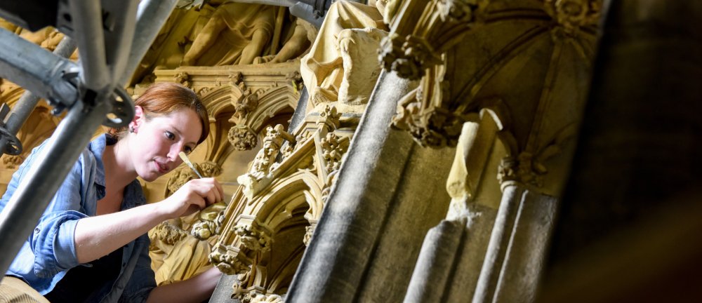 Eine Steinmetzin arbeitet an einem Portal des Kölner Doms.