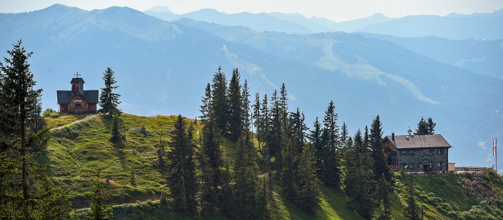 Kapelle auf Hügel mit Bergen im Hintergrund
